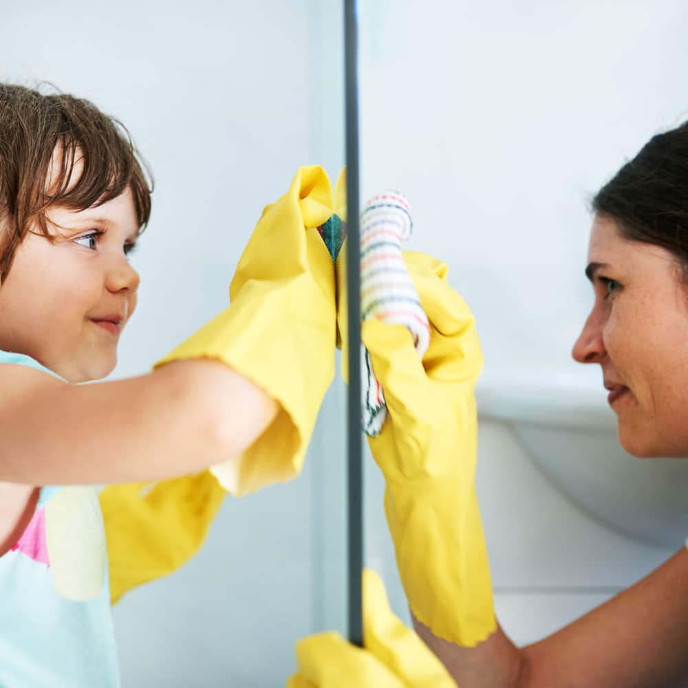 Mom and daughter cleaning a glass door together. 