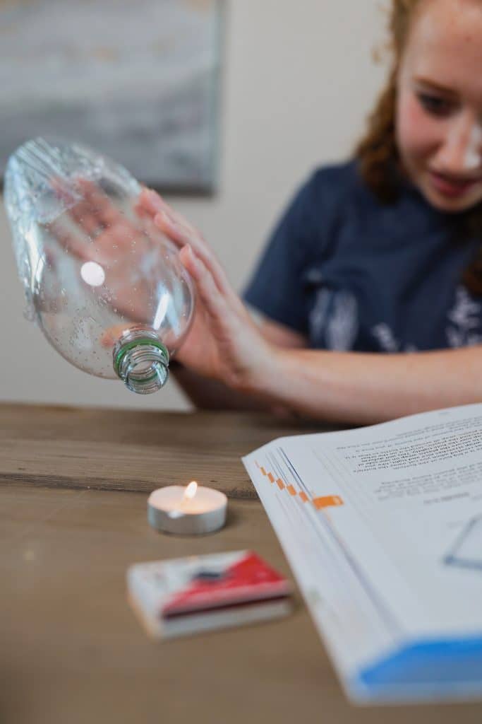 Student covering tea light with empty water bottle