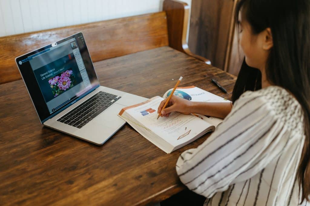 Student watching an Apologia course video and writing in her student notebook